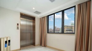 A hotel room with a large window, an elevator, and two trash bins. - Hualv Hotel (Guangzhou Children's Hospital Shangxiajiu Pedestrian Street Branch) (Guangzhou)