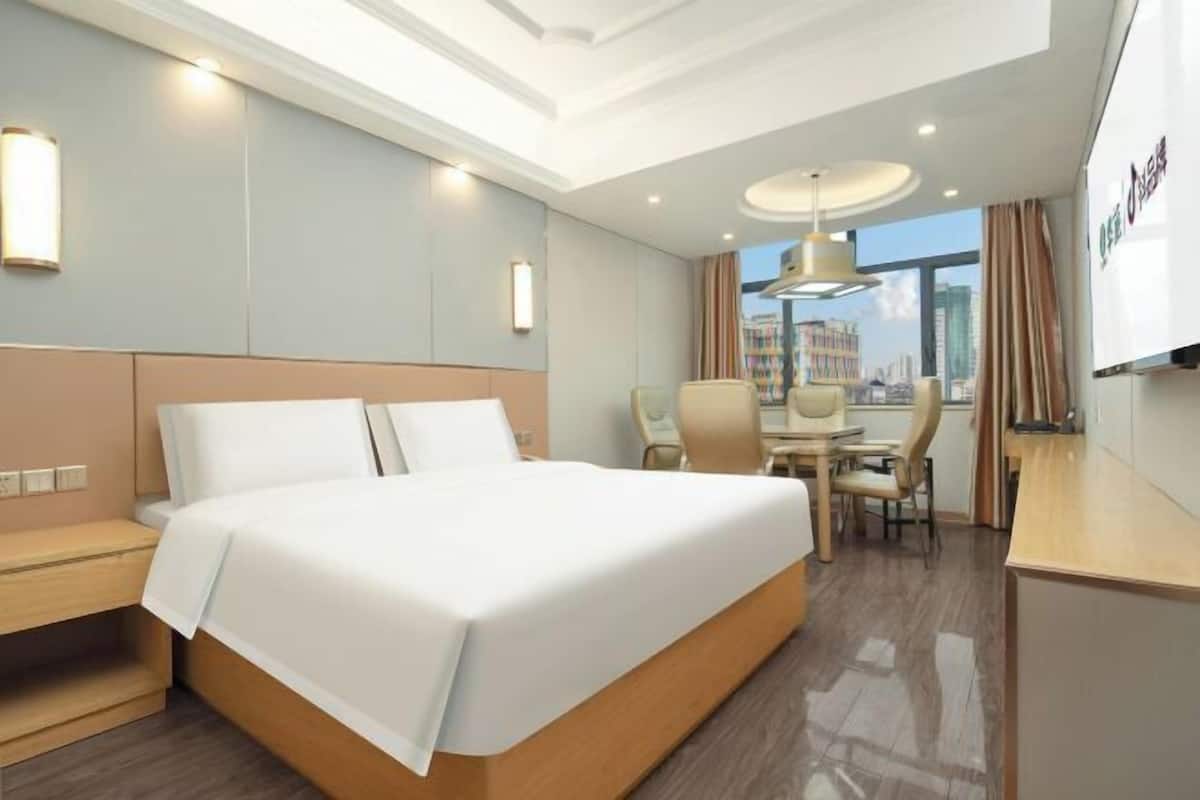 A hotel room with a large bed, a desk, and a chair.