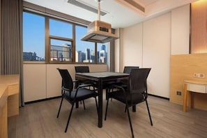 A modern dining area with a table and chairs, a city view through large windows, and a ceiling-mounted ventilation system. - Hualv Hotel (Guangzhou Children's Hospital Shangxiajiu Pedestrian Street Branch) (Guangzhou)