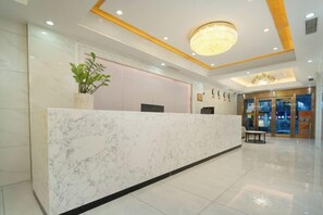 A hotel reception area with a marble counter, a reception desk, a potted plant, and a chandelier. - Hualv Hotel (Guangzhou Children's Hospital Shangxiajiu Pedestrian Street Branch) (Guangzhou)