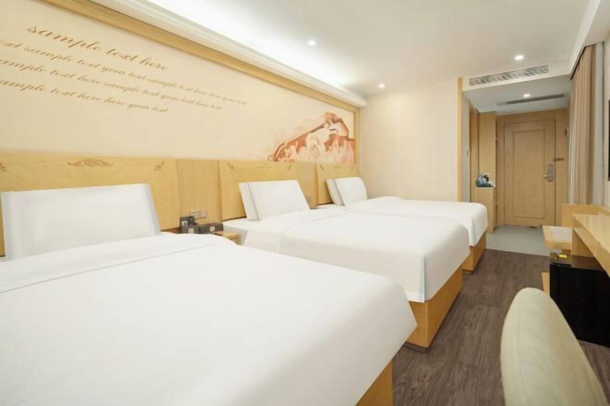 A hotel room with two beds, a wooden headboard, a desk, and a wall with a decorative text and image.