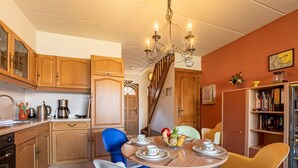 A cozy kitchen with wooden cabinets, a dining table set for four, and a chandelier. - Wonderful  villa for 4 people with WIFI and TV (Bruges)
