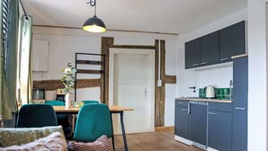 Eine kleine Küche mit dunklen Schränken, einem Holztisch und einer Pendelleuchte.