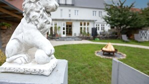 A white lion statue in a garden with a house in the background. - Cosy apartment for 2 guests with WIFI, TV, terrace and pets allowed (Neustrelitz)