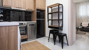 A modern kitchen with wooden cabinets, stainless steel appliances, and a black shelving unit. - Brand New 1 Bd Apt in Trendy Kipseli (Athens)