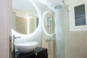 A modern bathroom with a glass-enclosed shower, a white sink, and a large mirror. - Brand New 1 Bd Apt in Trendy Kipseli (Athens)