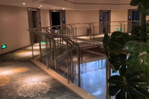 A hotel lobby with a glass railing, a water feature, and a large plant. - MU YA LI Hotel (Nanjing Olympic Center) (Nanjing)