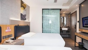 Una habitación de hotel moderna con una cama grande, un escritorio, un televisor y un baño con espejo y lavabo.