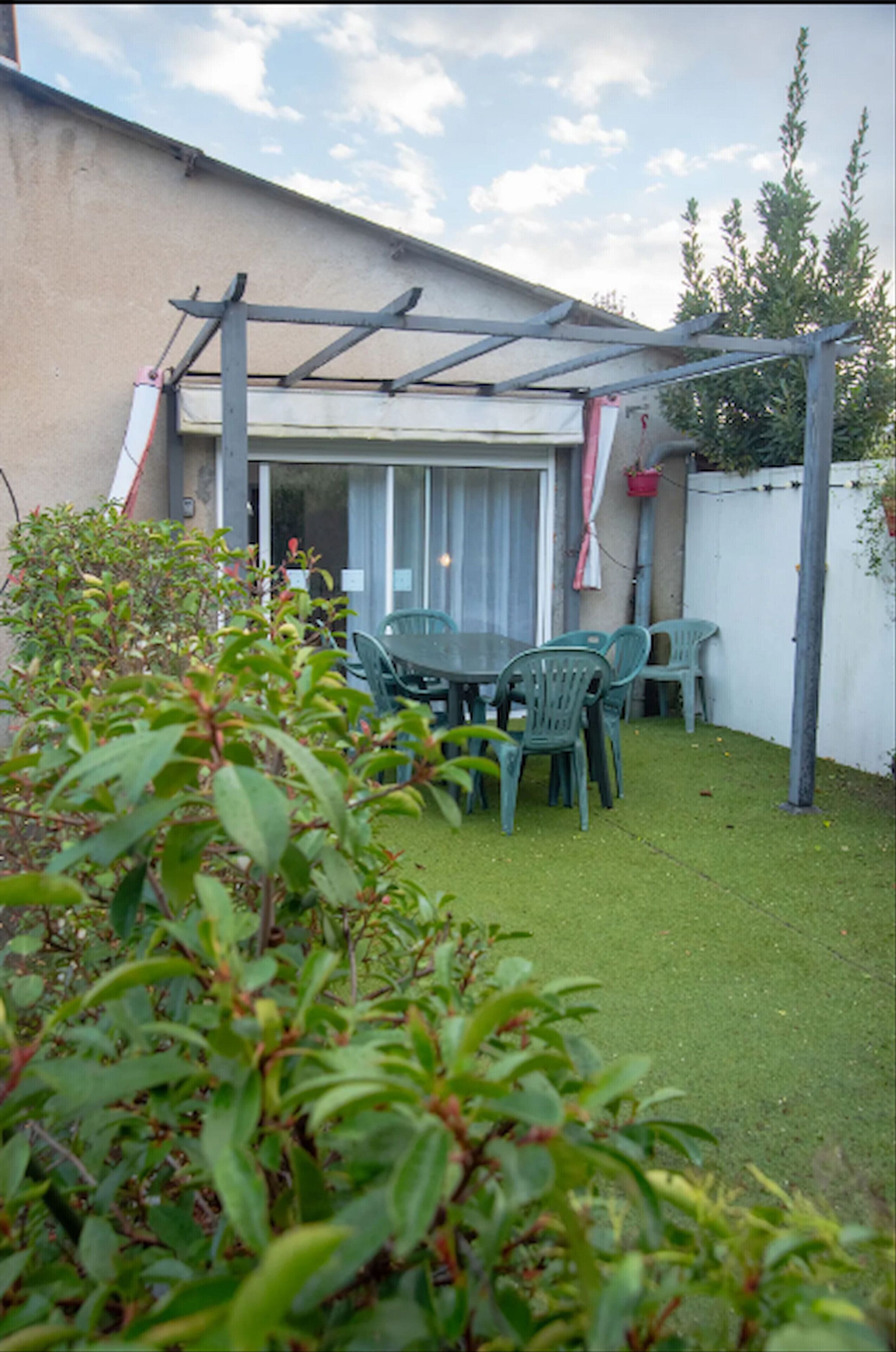 A patio area with a table and chairs, a pergola, and a white fence.