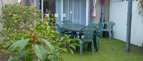 A patio area with a table and chairs, a pergola, and a white fence.