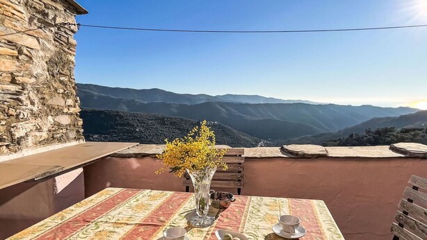 A table set with a vase of yellow flowers, a plate of food, and a cup on a table with a striped tablecloth, overlooking a mountainous landscape. - Stunning  villa for 4 people with WIFI, terrace and panoramic view (Prelà Castello)