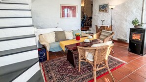 A cozy living room with a staircase, a fireplace, and a dining area with wicker furniture. - Stunning  villa for 4 people with WIFI, terrace and panoramic view (Prelà Castello)