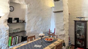 A dining area with a table set for two, a bookshelf, a clock, and a cabinet with glass doors. - Stunning  villa for 4 people with WIFI, terrace and panoramic view (Prelà Castello)