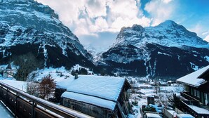 Un village de montagne aux bâtiments enneigés, offrant une vue dégagée sur les sommets environnants.