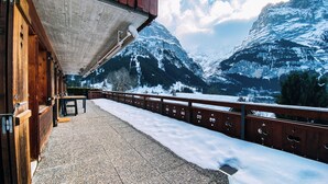 Un chalet en bois doté d’un balcon donnant sur des montagnes enneigées.