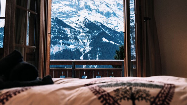 Une chambre avec une grande fenêtre donnant sur un paysage montagneux enneigé.