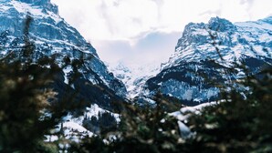 Un paysage montagneux avec des sommets enneigés et une vallée.