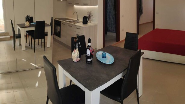 Un espacio habitable compacto con comedor, kitchenette y cama.