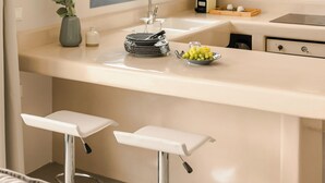 A kitchen with a window, a sink, a countertop, and two bar stools. - Villa Ivi - Zen Villas (Fiskardo)