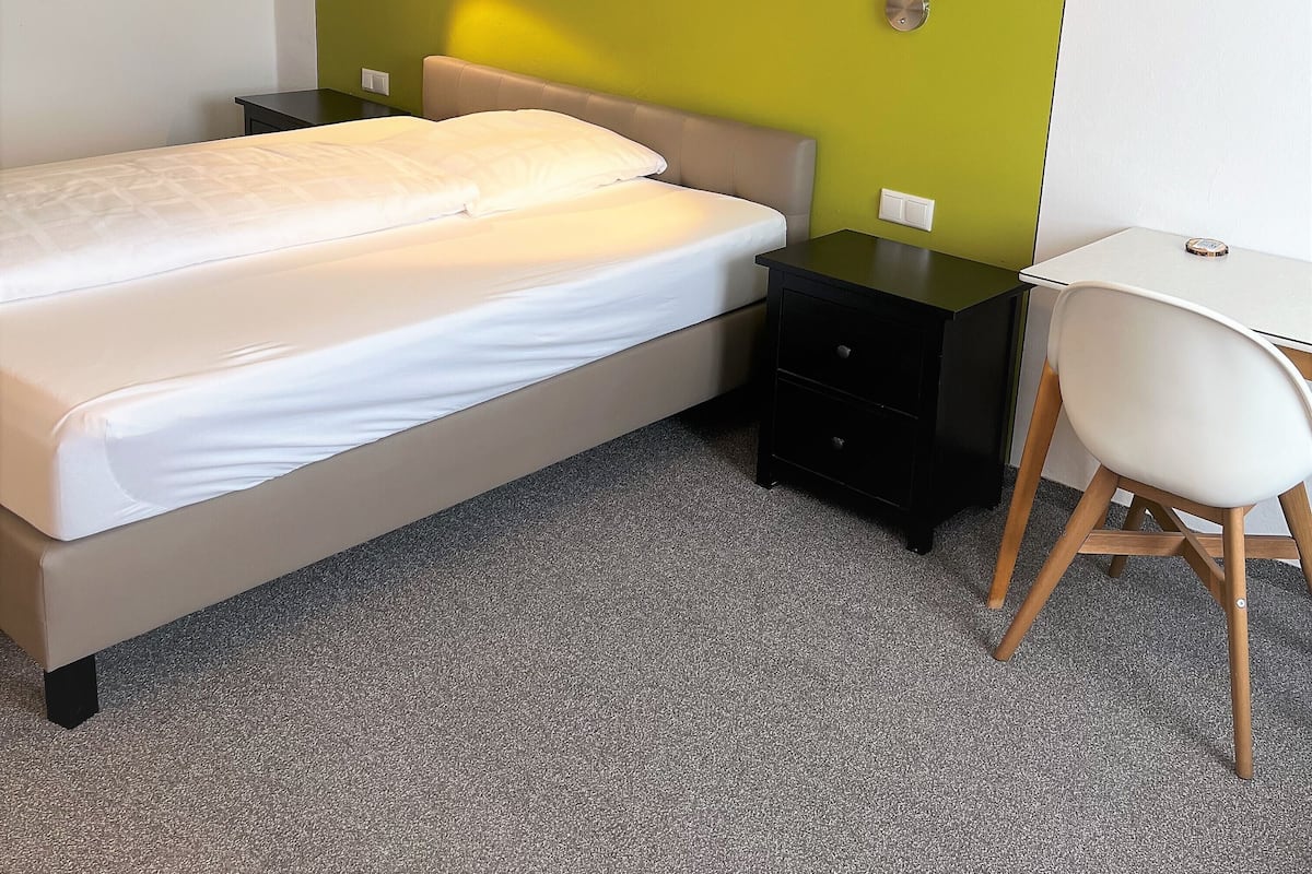 A modern bedroom with a bed, bedside tables, a desk, and a chair.