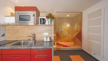 A modern kitchen with a built-in microwave, a sink, and red cabinets.
