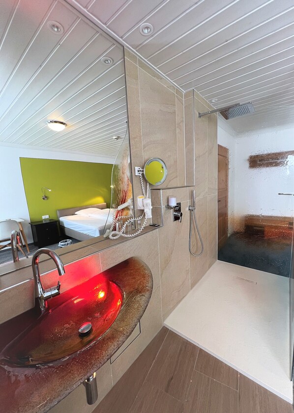 A modern bathroom with a red sink, a mirror, a shower, and a green accent wall. - Altötting City Apartments (Altötting)