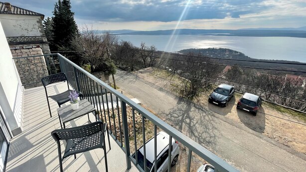 Un balcon donnant sur un lac et sur des voitures garées.
