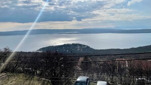 Une vue panoramique d’un lac, avec des montagnes lointaines, un ciel dégagé et une clôture au premier plan.