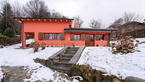 A modern house with a red facade, stone steps leading to the entrance, and a snowy landscape. - Alma e Basili by Wonderful Italy (Bellagio)