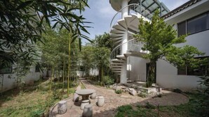 A modern house with a spiral staircase, a stone table with chairs, and a garden with bamboo and trees. - Taibai Restaurant Boutique Garden Hotel (West to Jining North Bus Station) (Jining)