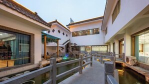 A courtyard with a wooden bridge over a water feature, surrounded by buildings with traditional architecture. - Taibai Restaurant Boutique Garden Hotel (West to Jining North Bus Station) (Jining)