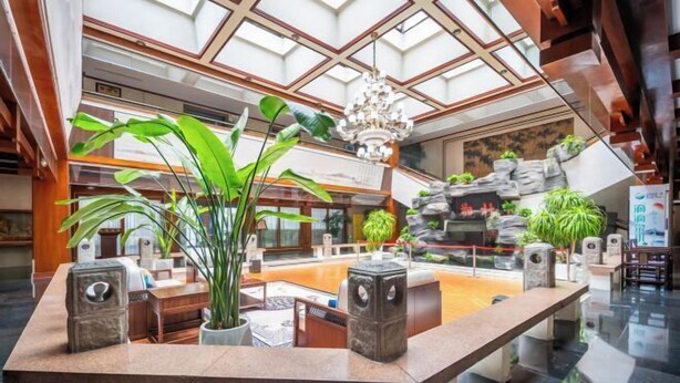 A spacious lobby with a high ceiling, a central fountain, and multiple seating areas. - Taibai Restaurant Boutique Garden Hotel (West to Jining North Bus Station) (Jining)