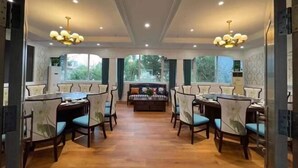 A spacious dining area with a central seating arrangement, large windows, and a chandelier. - Taibai Restaurant Boutique Garden Hotel (West to Jining North Bus Station) (Jining)