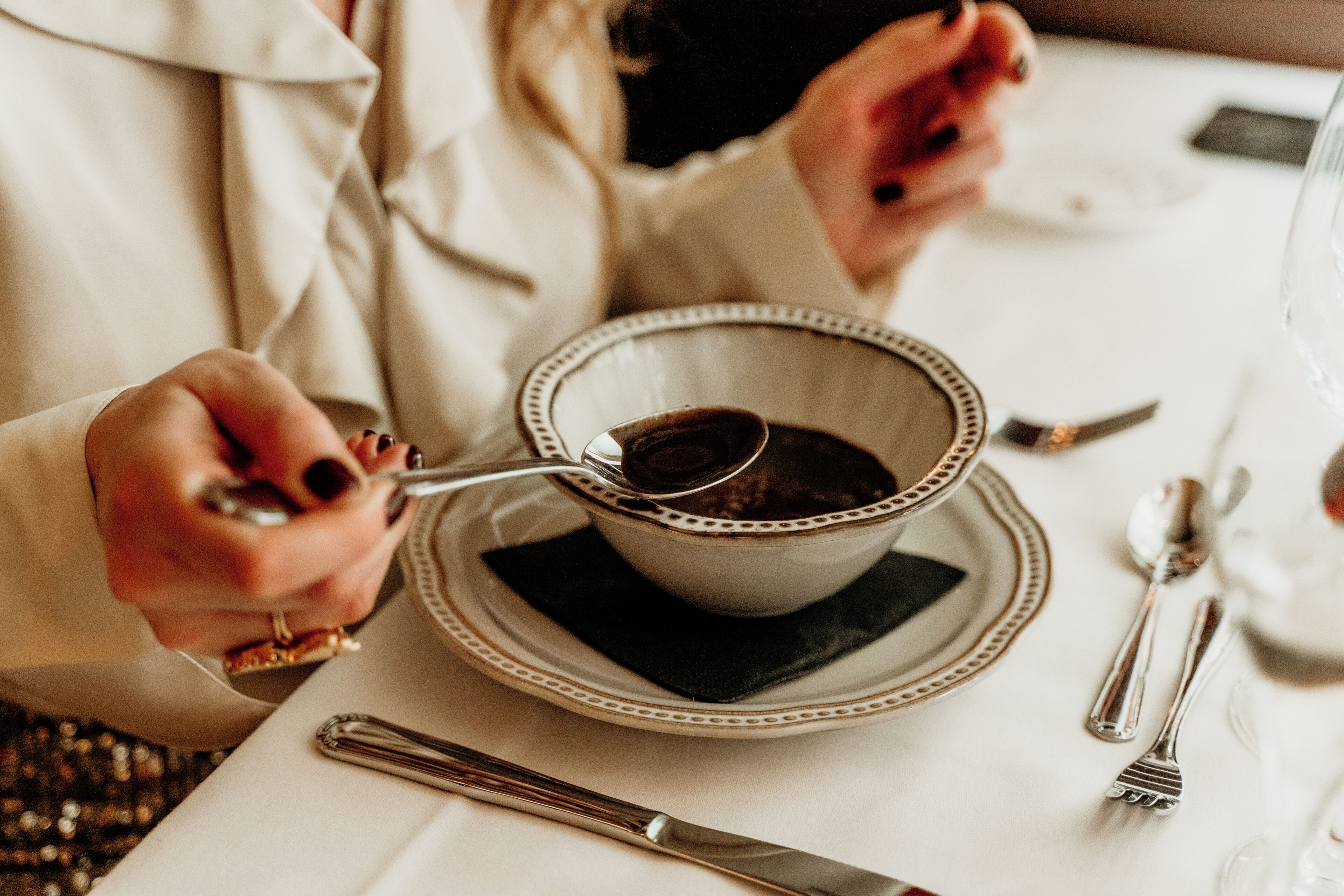 A dining table with a cup of coffee, a spoon, a fork, and a knife.