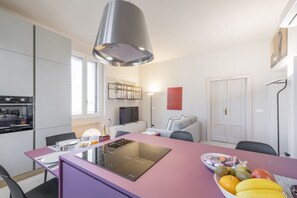 A modern kitchen with a central island, a dining area, and a living space with a sofa.