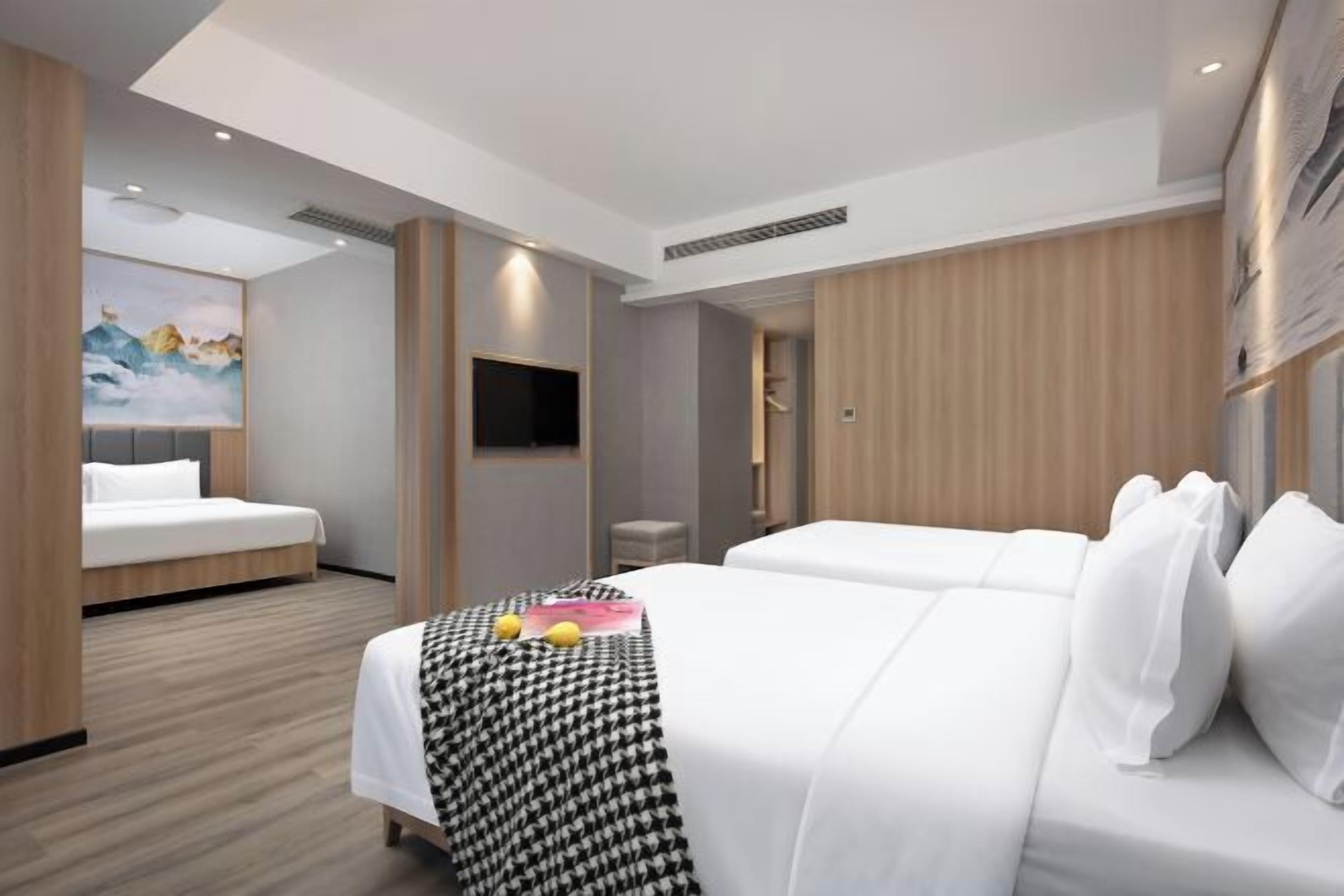 A hotel room with a bed, a TV, and a painting on the wall.