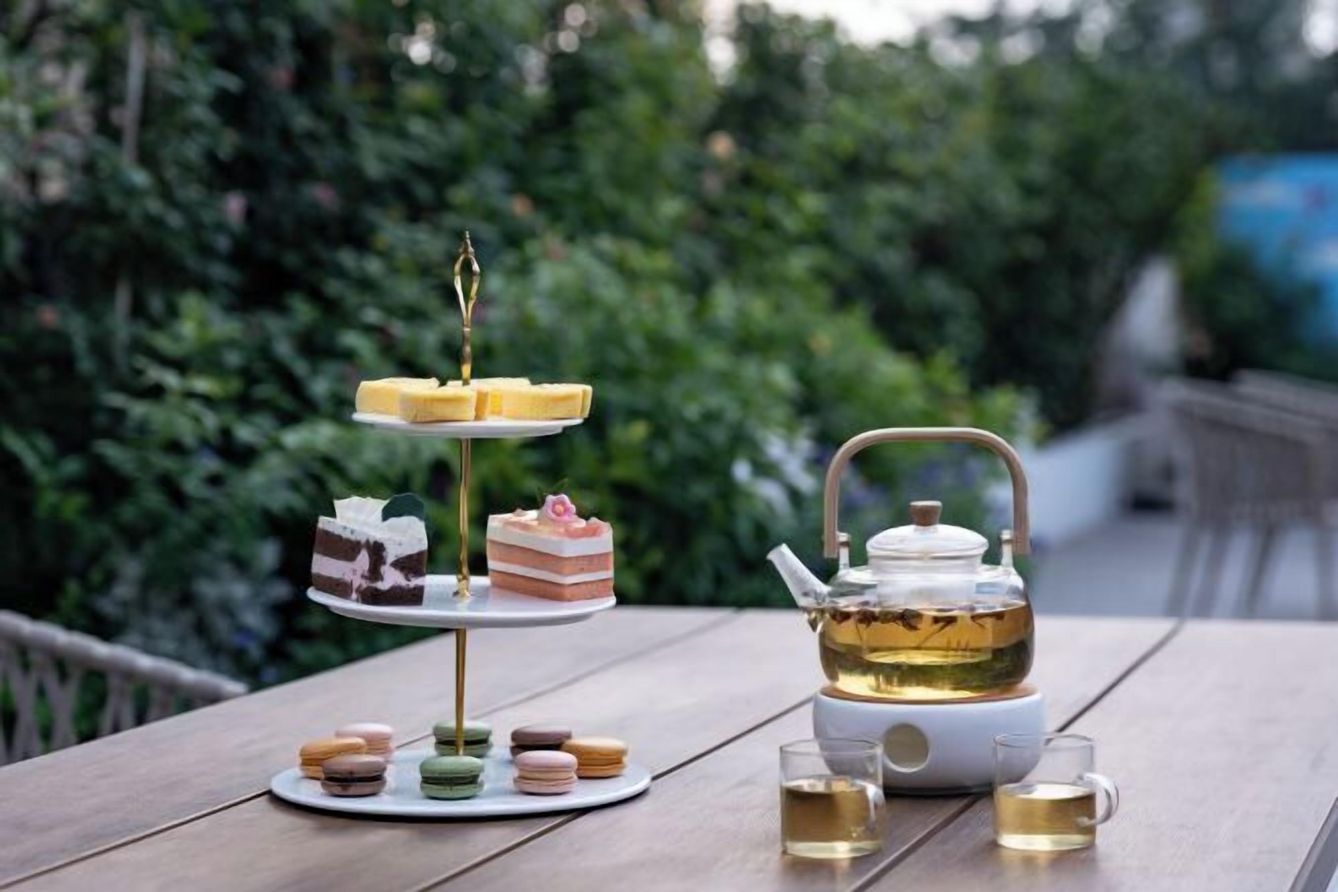 A table with a tea set, two tiered dessert stands, and macarons.