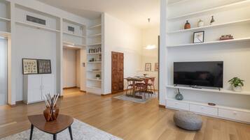Ein modernes Wohnzimmer mit Flachbildfernseher, Holzboden und eingebauten Regalen.