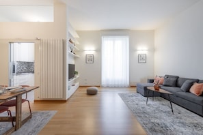 A modern living room with a sofa, a dining table, and a kitchen area. - SEMPIONE, 51 – Spacious and bright (Milano)