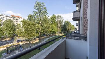 Ein Balkon mit Blick auf einen Park, einen Fußweg und Wohnhäuser.