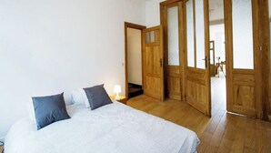 A bedroom with a bed, wooden wardrobe, and a door leading to another room. - Beautiful 2-bedroom artist's apartment with all comforts in the heart of Saint-Gilles (Saint-Gilles)