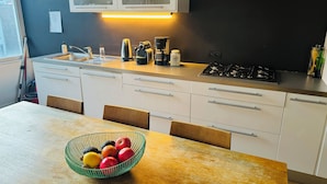 A modern kitchen with white cabinets, a stainless steel sink, a coffee maker, and a bowl of fruit on the table. - Beautiful 2-bedroom artist's apartment with all comforts in the heart of Saint-Gilles (Saint-Gilles)