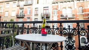 A balcony with a table, two wine glasses, and a bottle of wine. - Beautiful 2-bedroom artist's apartment with all comforts in the heart of Saint-Gilles (Saint-Gilles)