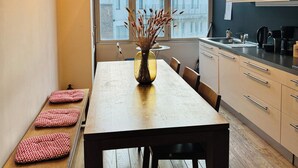 A modern kitchen with a wooden dining table, bench seating, and a vase with dried plants. - Beautiful 2-bedroom artist's apartment with all comforts in the heart of Saint-Gilles (Saint-Gilles)