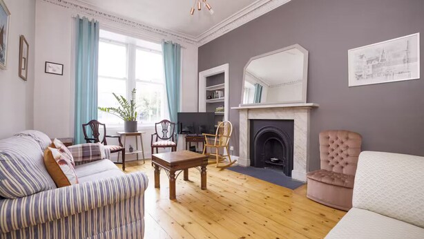 A living room with a sofa, chairs, a fireplace, and a television. - Splendid 2bed Apt near Haymarket (Edinburgh)