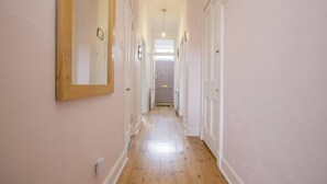 A narrow hallway with wooden flooring and white walls, leading to a door at the end. - Splendid 2bed Apt near Haymarket (Edinburgh)