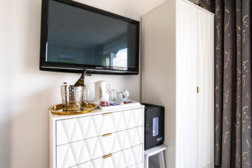 A minibar with a television above it, a coffee maker, and a small refrigerator.
