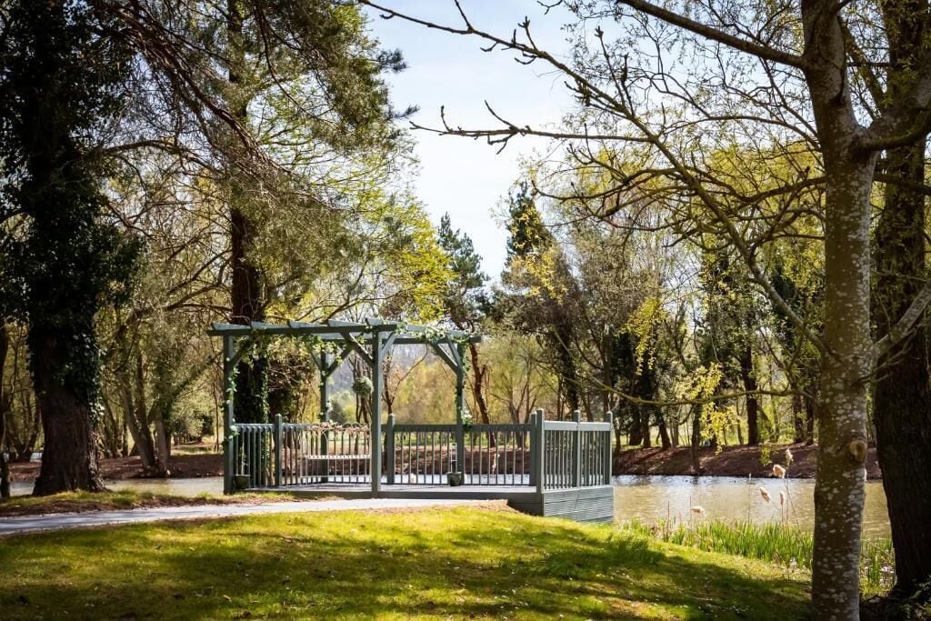 Un pabellón en un parque con un estanque y árboles.