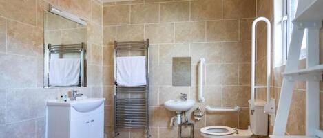 Un baño moderno con lavamanos, espejo, toallero, inodoro y zona de ducha.