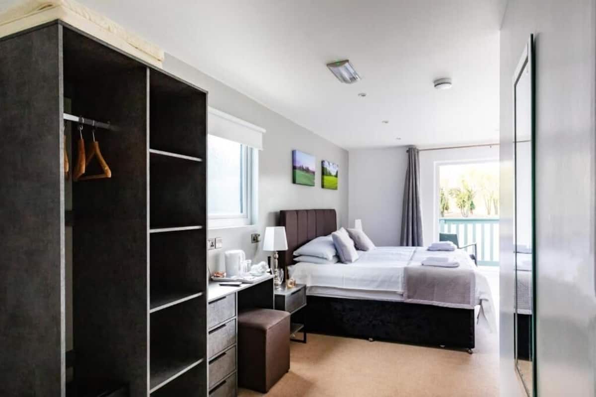 A bedroom with a bed, bedside table, lamp, and a large wardrobe.